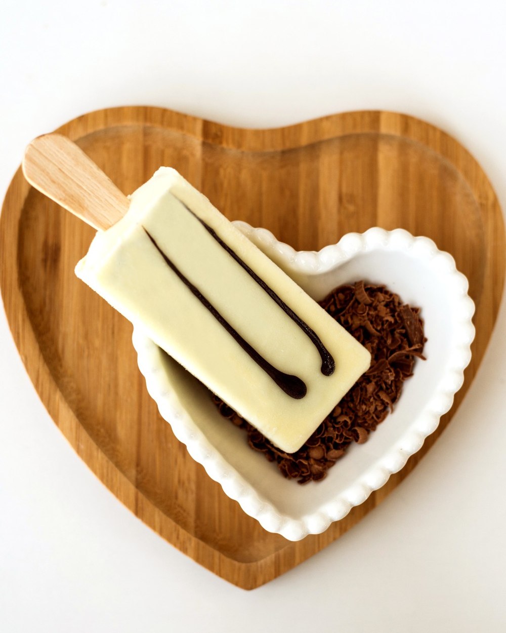 Picolé Bliss de chocolate branco servido em prato de coração com raspas de chocolate
