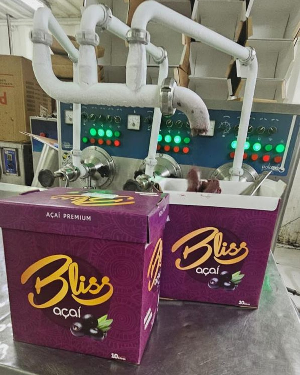 Máquina de produção da Bliss com o painel aceso e caixas de Açaí Premium saindo da linha